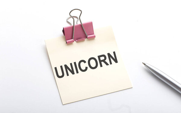 UNICORN текст на наклейке с ручкой на белом фоне