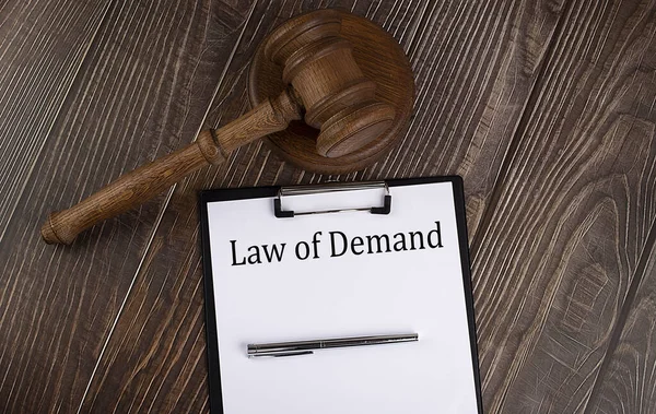 LAW OF DEMAND text on the paper with gavel on wooden background