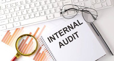 Not defterine klavye, grafik ve gözlük ile yazılmış INTERNAL AUDIT metni