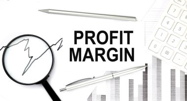 Belge üzerindeki PROFIT MARGIN metni kalem, grafik ve büyüteç, hesap makinesi