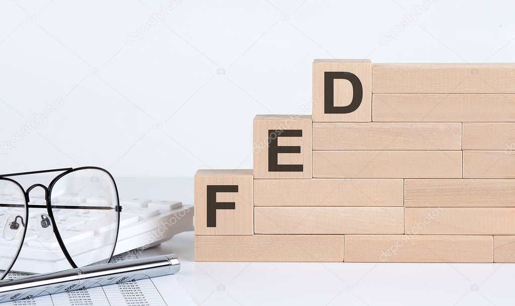 Three wooden cubes with letters FED on white table with keyboard and glasses