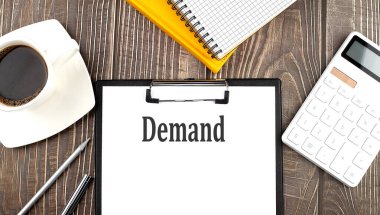 DEMAND, kahve, hesap makinesi ve defterle kağıda yazılı. İş dünyası