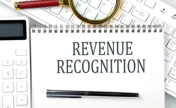 REVENUE RECOGNITION . Text on notepad with calculator and keyboard,business