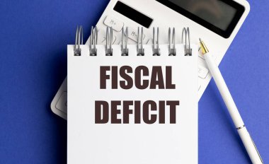 Defterde hesap makinesi ve mavi arkaplan kalemli mali açık metni, bütçe açığı kavramı. 