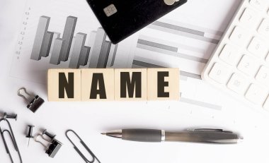 Dosya, kredi kartı, kalem ve hesap makinesi olan bir ofis masasının üzerinde tahta bloklar var. . 