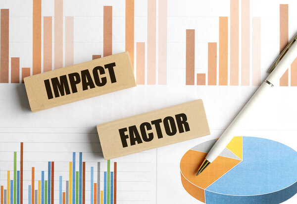 Деревянные блоки со словом импакт-фактор на финансовых диаграммах с ручкой, представляющей анализ и показатели производительности . 
