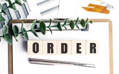 Tahta bloklara yazı tahtası, bitki, çizelge ve beyaz ofis arka planında gümüş kalem sipariş et.. 