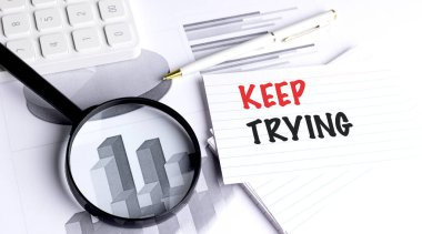 Çizgili karttaki motive edici mesajı büyüteç, kalem ve hesap makinesiyle çizelgelerde denemeye devam et..