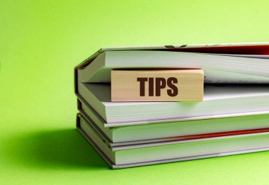 Yeşil arkaplan üzerine istiflenmiş açık kitapların arasına sözcük ipuçları yerleştirilmiş tahta blok . 