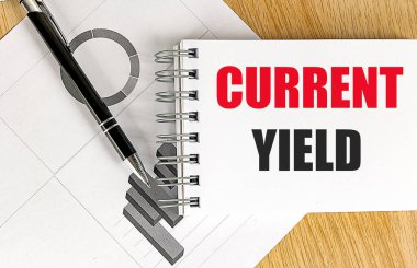 Siyah kalem ve ahşap masadaki finansal çizelgelerle birlikte sarmal defterde mevcut verim cümlesi . 