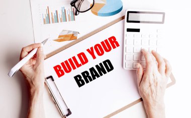 İşletme gelişimini temsil eden kalem ve hesap makinesi olan ellerle markanızı oluşturan metin panosu.