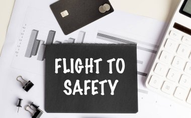 Çizelgeler, kredi kartı, hesap makinesi ve ofis araçlarıyla siyah kağıt üzerinde güvenlik kavramına uçuş.