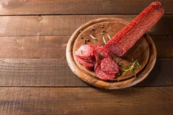 Kiełbasy salami na drewnianym stołem — Zdjęcie stockowe