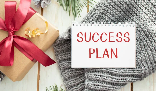 Notepad with the text SUCCESS PLAN, lies on the laptop and a gift box next to it