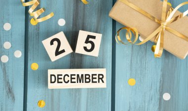 25 Aralık tarihli ahşap takvim blokları Noel Günü 'nü bokeh ışıkları, siyah beyaz bufalo kontrolü ve kırmızı boncuk çelengi ile kutluyor. Kopyalama alanı olan üst görünüm.