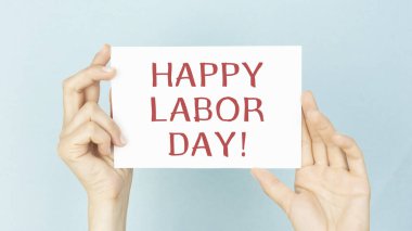 Takım elbiseli bir adam, yazılı mutlu işçi günü tabelasını gösteriyor.