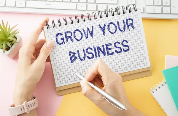 holding a card with text GROW YOUR BUSINESS, business concept image with soft focus background
