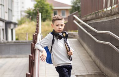 Evinin önündeki ilkokul öğrencisi Sırt çantasıyla gülümsüyor