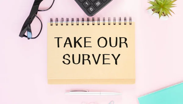 Take Our Survey. written on notepad with pencil on pink background. Business concept.