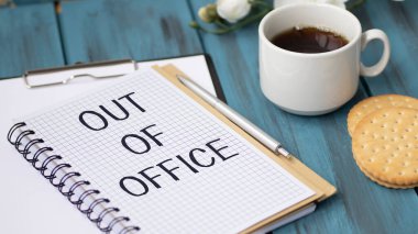 Ofis dışı mesajı olan defter ahşap ofis masasının üstünde..