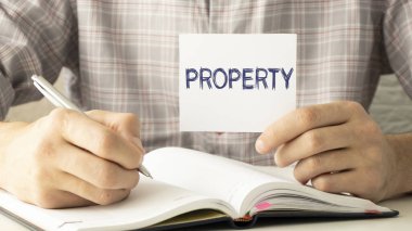 Emlak koruma kavramı. Mülk sigortası bir sigorta acentesinin elinde tuttuğu beyaz bir kağıda yazılır. Yüksek kalite fotoğraf