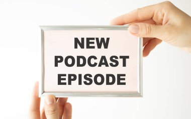 Kırsal ahşap masadaki podcast kayıt ekipmanlarının en üst görüntüsü. Spiral not defterinde yeni podcast bölümü yazıyor.