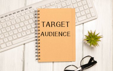 Klavyede siyah keçeli kalemle beyaz arkaplan üzerinde TARGet AUDIENCE metni olan bir kağıt parçası