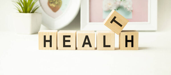 Текстовое сердце из деревянных кубиков и стетоскопа на цветном фоне