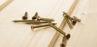 Tahtada üç altın vida, beyaz arka plan..