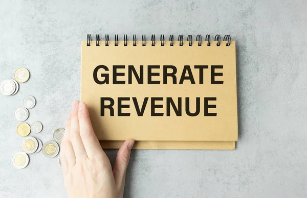 woman hand writing a note with a fountain pen on a notebook. Handwritten text GENERATE REVENUE, business success concept