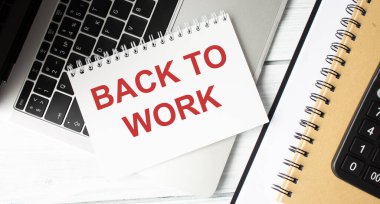 Notebook with text BACK TO WORK. Notebook on desk with graph and a notepad