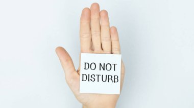 Adhesive paper on the palm of the hand with the text Do Not Disturb