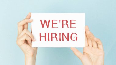 Tablet pc with text We're hiring which holding hands