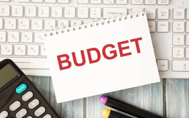 Kağıt üzerinde dizüstü bilgisayarlı bütçe metni ve ahşap masa üzerinde keçeli kalemler - iş, bankacılık, finans ve yatırım konsepti