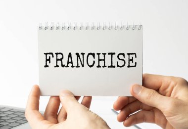 Beyaz arka planda izole edilmiş bir iş adamı tarafından gösterilen kağıtta bekleme sözcüğünü göster. Metin FRANCHISE