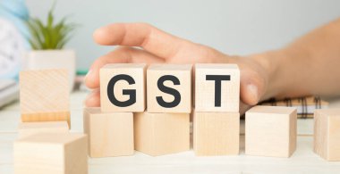 Tahta blokta GST kelimesi yazıyor. Ahşap masa üzerinde GST metin desing, konsept.