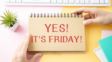 Üzerinde EVET yazan bir not. - Cuma günü. Ofis masasının arka planında bir çalışanın ellerinde.