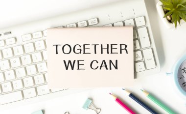 Notepad with Together We can text on klavye ile keçeli kalemler ve hesap makinesi ile ahşap zemin üzerinde.