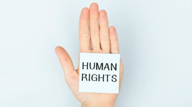 İçinde insan hakları yazılı bir kağıt parçasıyla genç bir adamın ellerini çarpıcı bir şekilde yakın plan çekiyoruz.