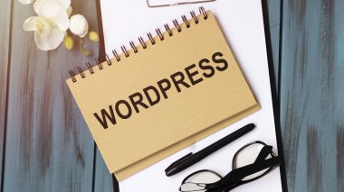 Tahta arka planda WordpresSS sözcüğüyle yazılmış bir defter. İş Konsepti.