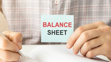 Notepad 'in beyaz arka planda işaretli, çizelgeli ve gözlüklü olduğu Balance SHEET kelimesi. İş dünyası