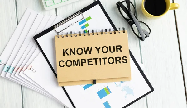 On a sheet of diary the inscription KNOW YOUR COMPETITOR, next to a pencil pointing to it, and glasses.
