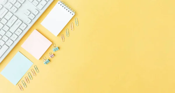 home office desk with plants, sticky tape and keyboard on yellow background top view mock up