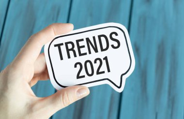 Mavi arkaplanda elinde TRENDS 2021 yazılı kağıt