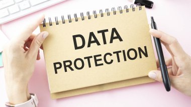 Ofis masasının arka planında DATA PROTECTION sözlerinin olduğu not.