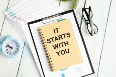 Seninle başlıyor, beyaz kağıt üzerinde, arka planda, kalem ve hesap makinesinin yanında.