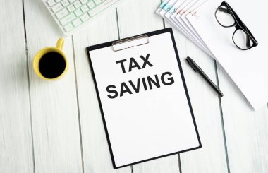 Not defterindeki Vergi Tasarrufları 'na hesap makinesi, klipler ve mali rapordaki kalemle birlikte metin yaz. Finansal ve iş konsepti fotoğrafı