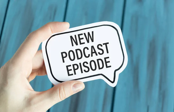 Kırsal ahşap masadaki podcast kayıt ekipmanlarının en üst görüntüsü. Spiral not defterinde yeni podcast bölümü yazıyor.