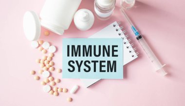 Bağışıklık sistemi. İlaçlar ve şırıngalar pembe masanın üzerinde. Bağışıklık sistemi kelimesi tıbbi kavram olarak kullanılıyor..