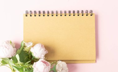 Beyaz ahşap arka planda şakayık çiçekleri ve yazı için yeri olan boş bir defter. Yukarıdan görüntüle.